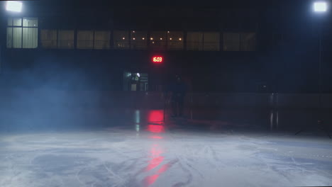 Man-hockey-player-with-a-puck-on-the-ice-arena-shows-dribbling-moving-directly-to-the-camera-and-looking-straight-into-the-camera